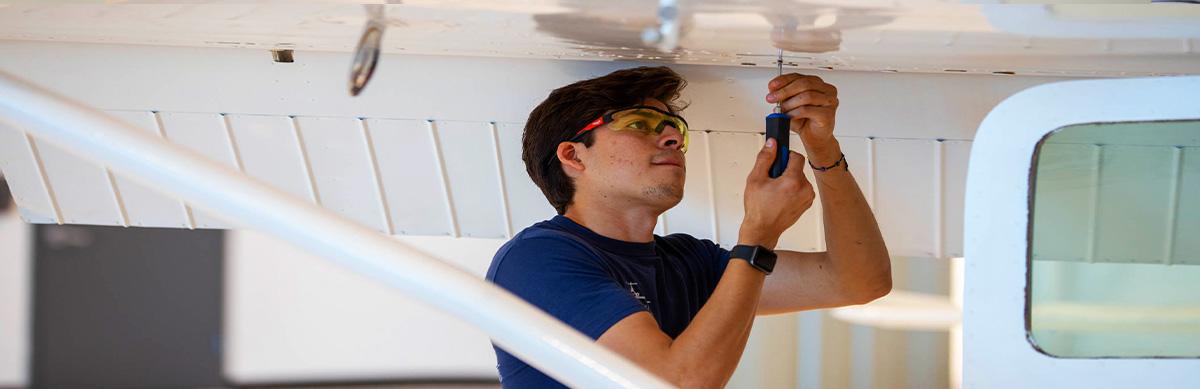 An aviation student works on the airframe of a plane